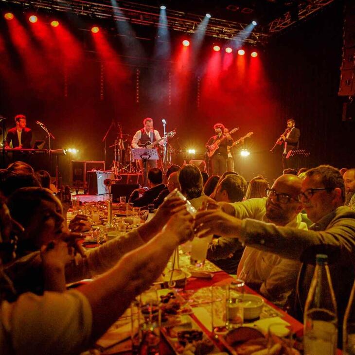 mensen toasten feestelijk, op de achtergrond een band op het podium